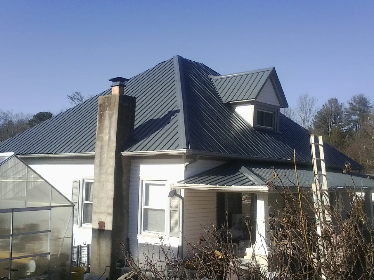 Dark blue standing seam metal roof on a white farmhouse with dormer — Slate & Tile Roof Repair by Roofing Brothers in Wyckoff