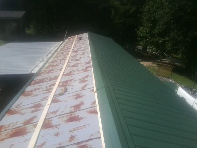 Old rusted panels beside newly installed green metal roofing — Wind Damage Roof Repair by Roofing Brothers in Wyckoff