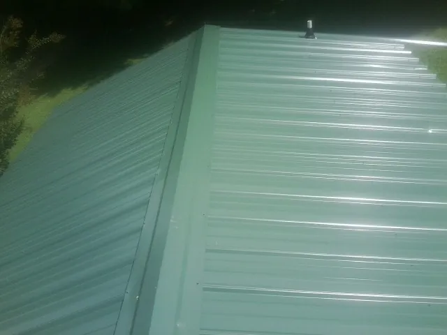 New green metal panels meeting at the ridge of a roof — Flat Roof Repair work by our crew in Wyckoff