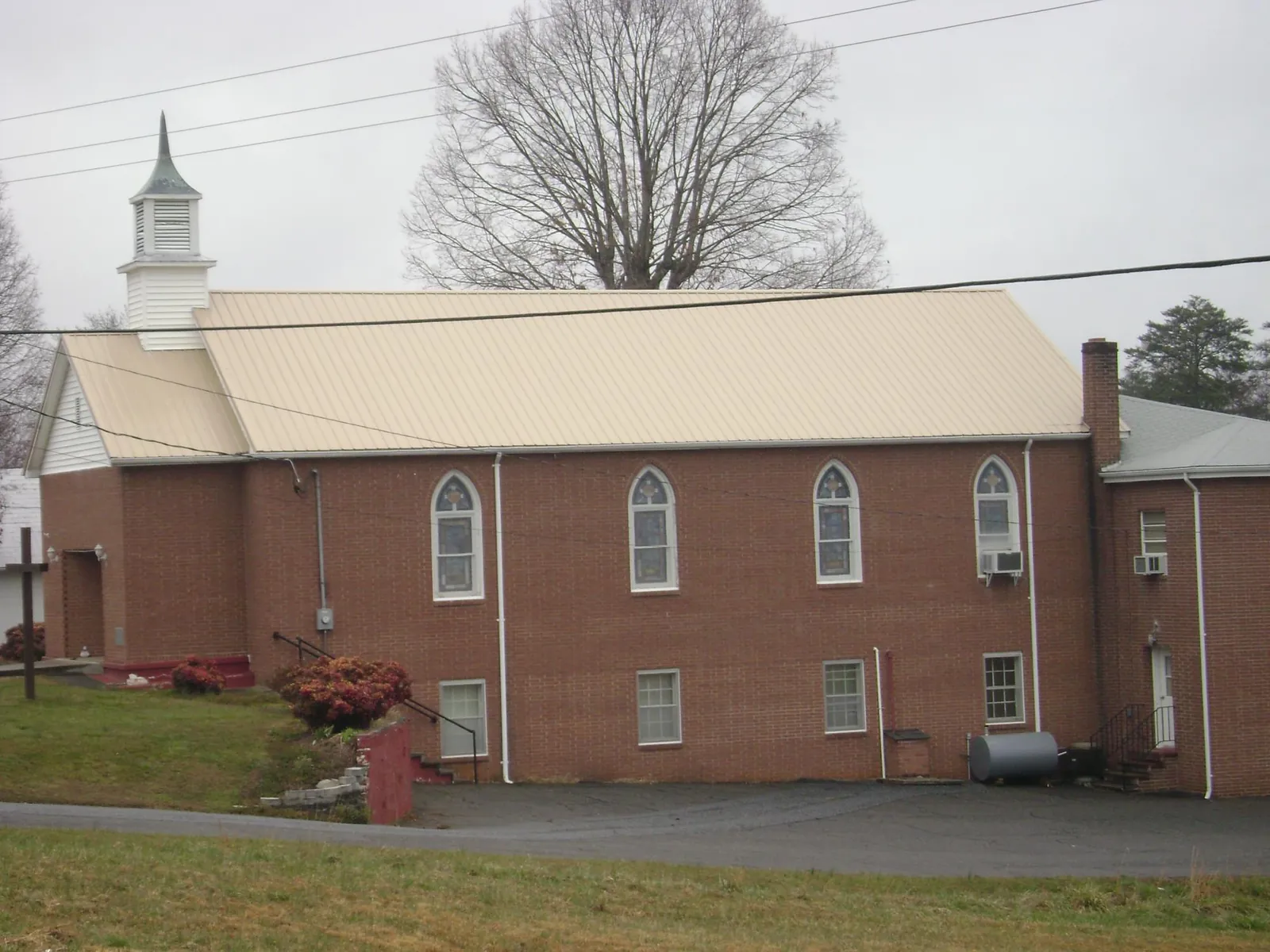 New tan metal roof on a brick church with a white steeple in Wyckoff