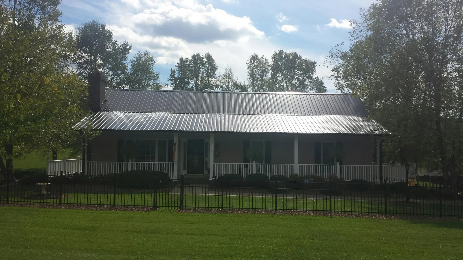 Gray metal roof on a brick ranch with a full width front porch — Gutter Guard Installation work by our crew in Wyckoff