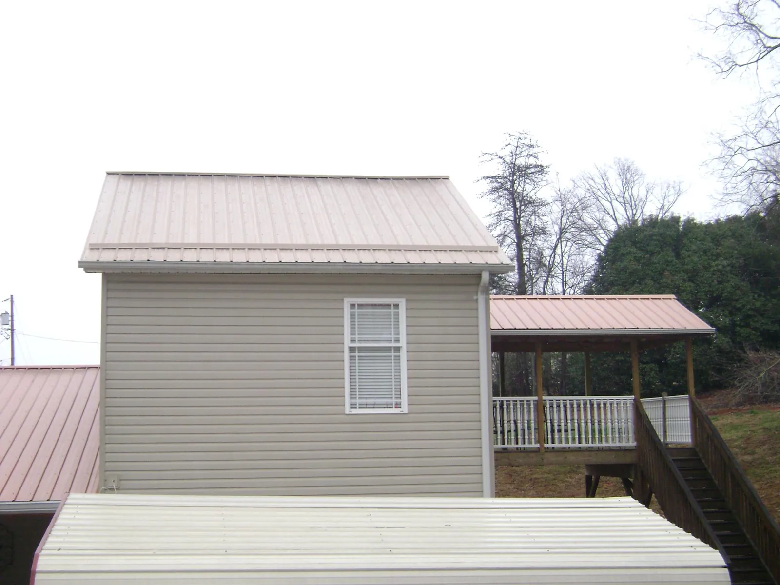 Tan metal roofs on a two story addition and attached porch, from a Roof Replacement job in Wyckoff