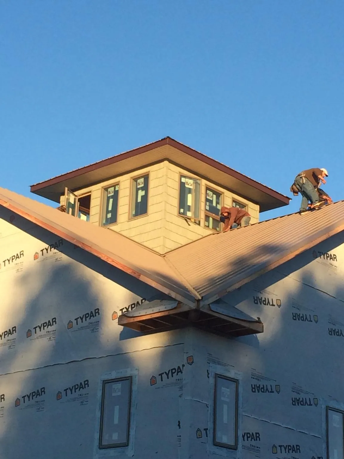 Roofers working around a rooftop cupola on a new metal roof at sunset — Roof Waterproofing in Wyckoff by Roofing Brothers